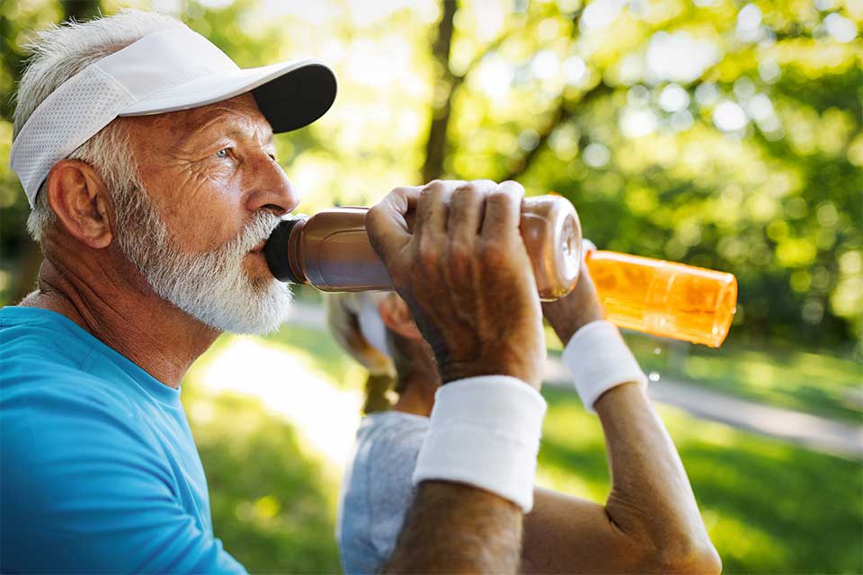 Elderly couple drinking water from water bottles after working out