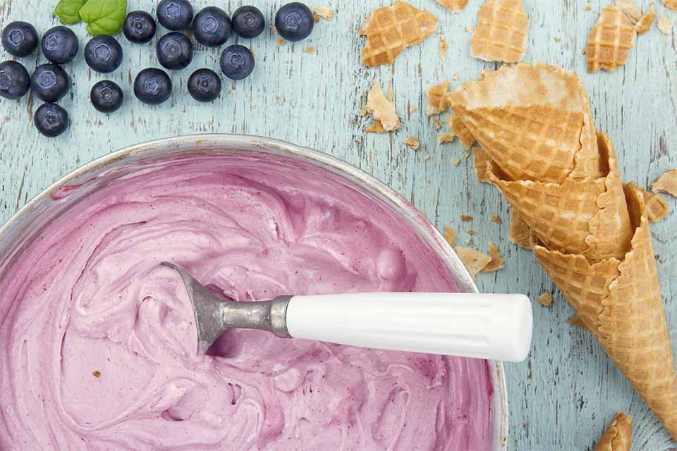 Pink ice cream with an ice cream scoop and ice cream cones