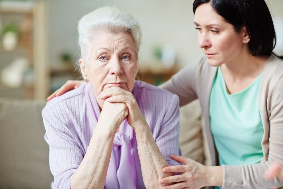 Daughter sits with upset elderly mother.