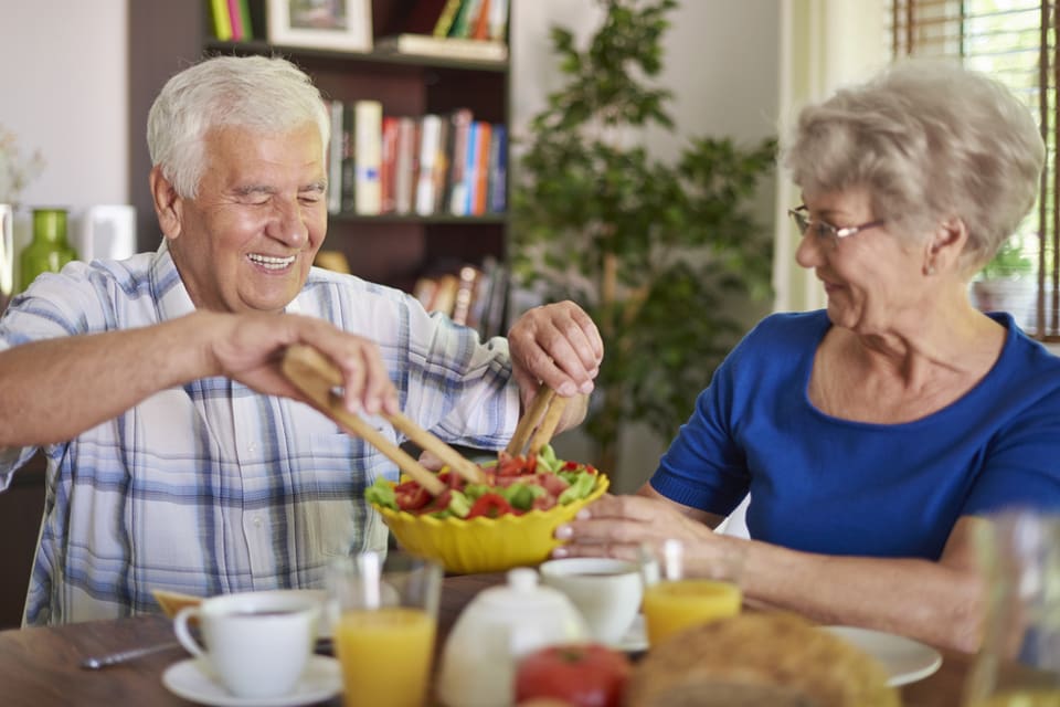 Elderly couple serving a bowl of salad