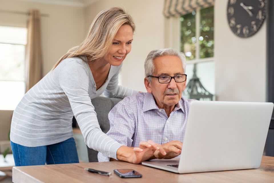 Younger woman and older man looking at computer for memory care help.