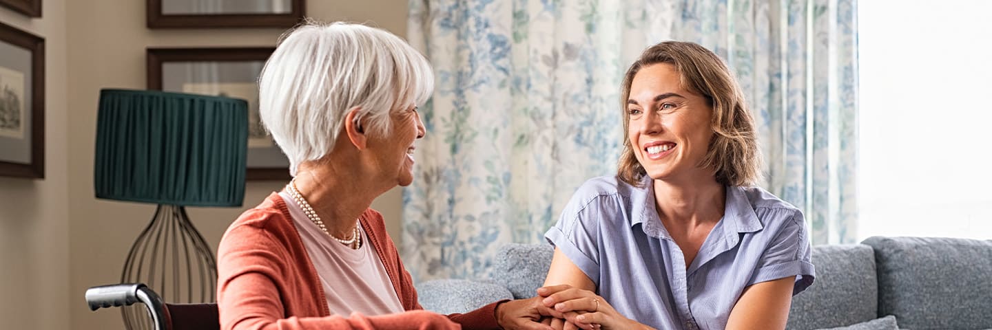 Senior and caregiver chatting in their living space