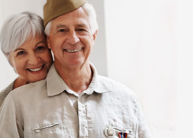 Grinning veteran hugged from behind by his happy partner.