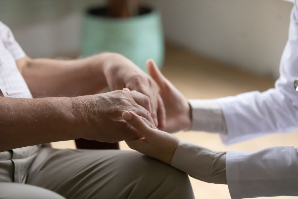 Caregiver consoles man with late stage dementia.