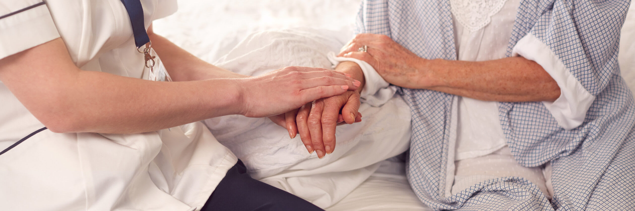 A closeup of the hands of a nursing assistant touching the hands of a senior in support