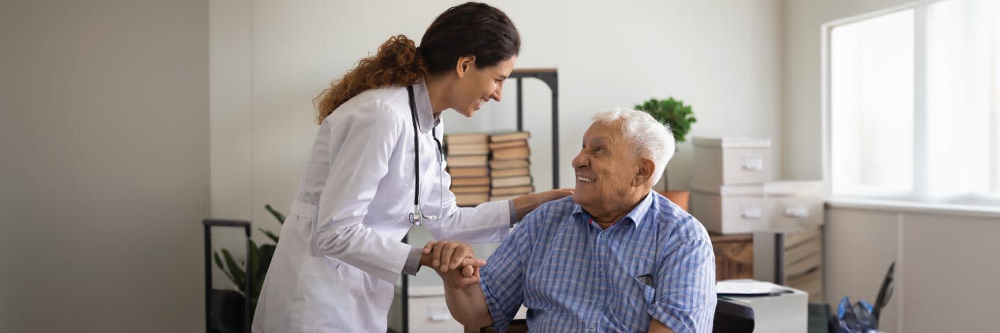 A doctor comforts an older male patient in her office