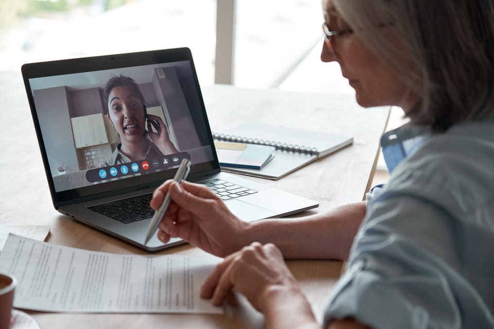 A senior woman virtually meets with someone on her laptop.