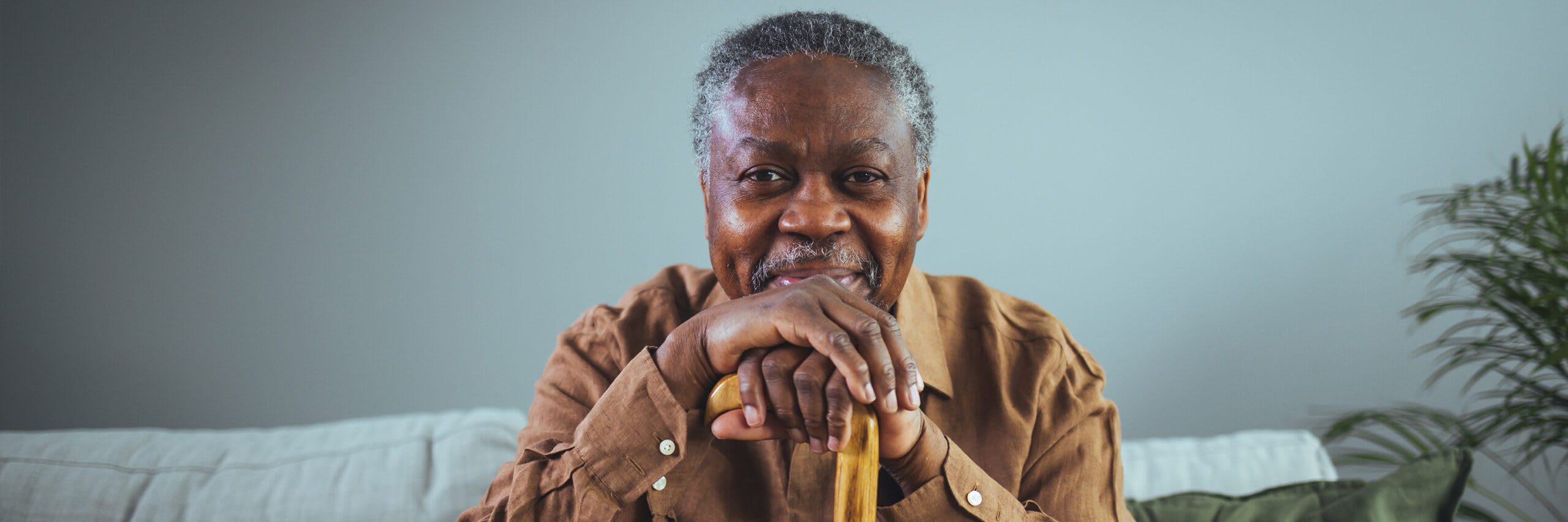 A senior man smiling while holding a cane