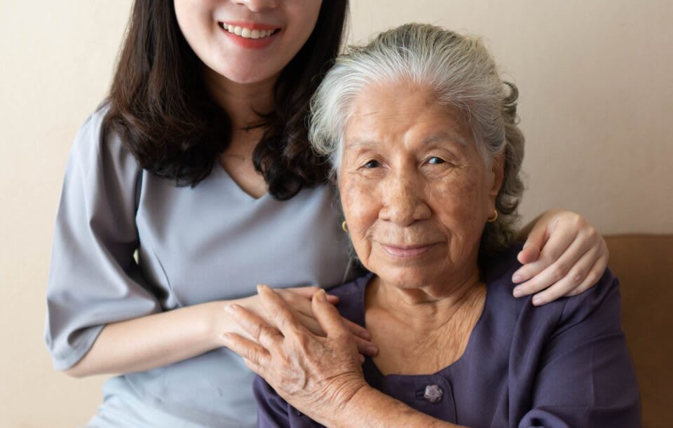 Caregiver with hand on the shoulder of an elderly woman