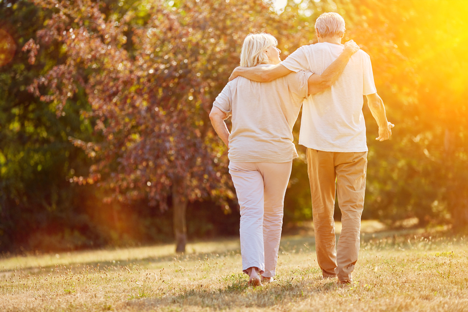 Older man & woman walking arm and arm in the evening sun