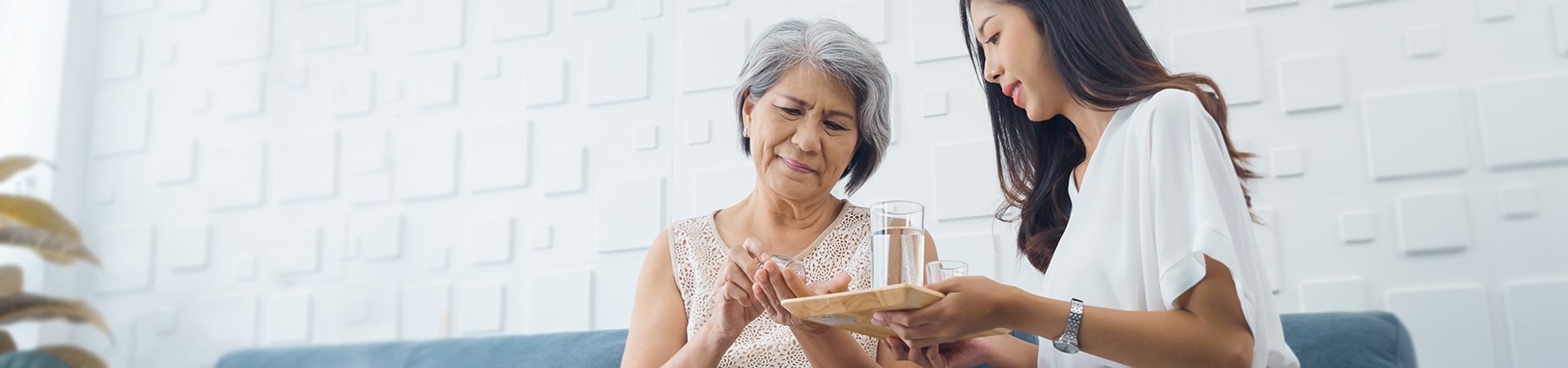 A caregiver assisting a senior woman with medication