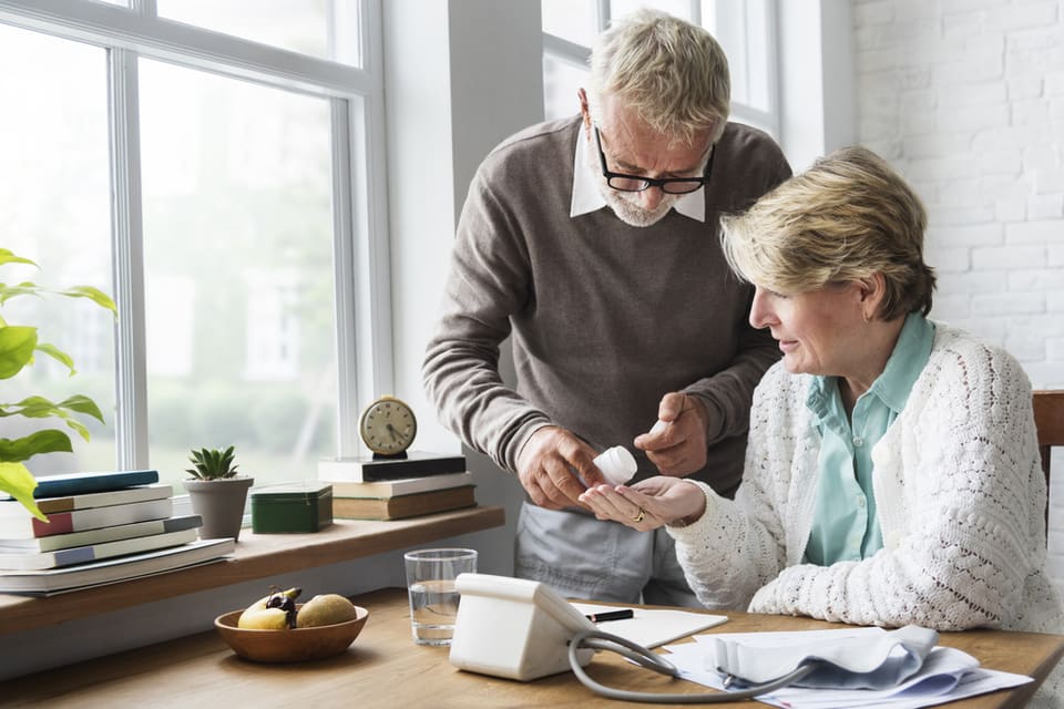 A senior man and woman prepare to take medication after researching which medications are liked to memory loss.