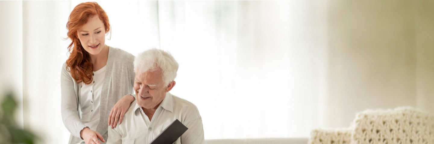 A young woman looks at a photo album with her senior father