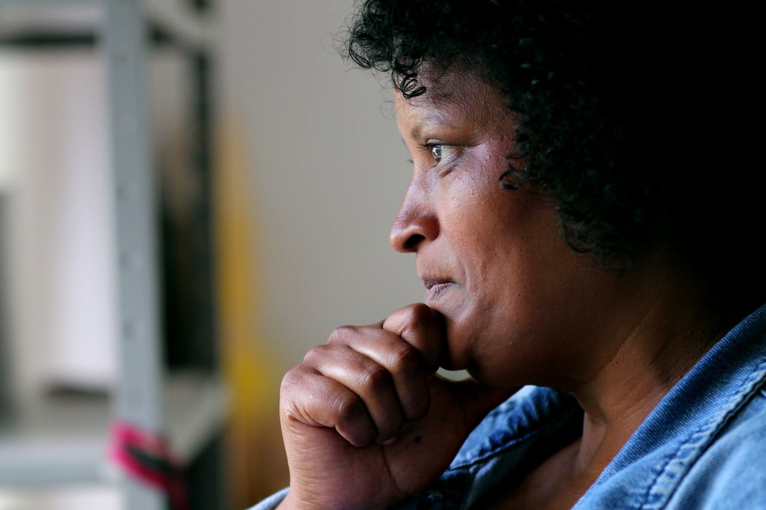 A woman sits while resting her hand on her chin.