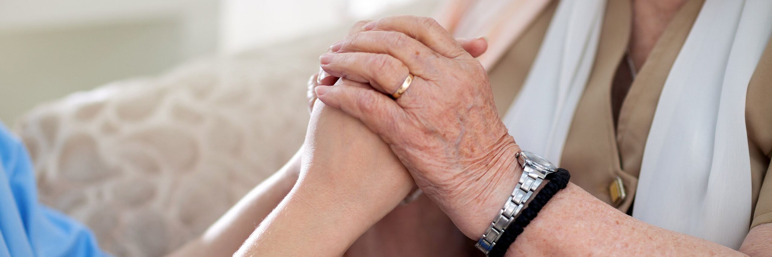 A closeup of a senior's hands holding the hands of a caregiver