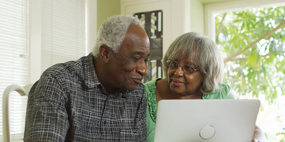 Two seniors looking at a computer together