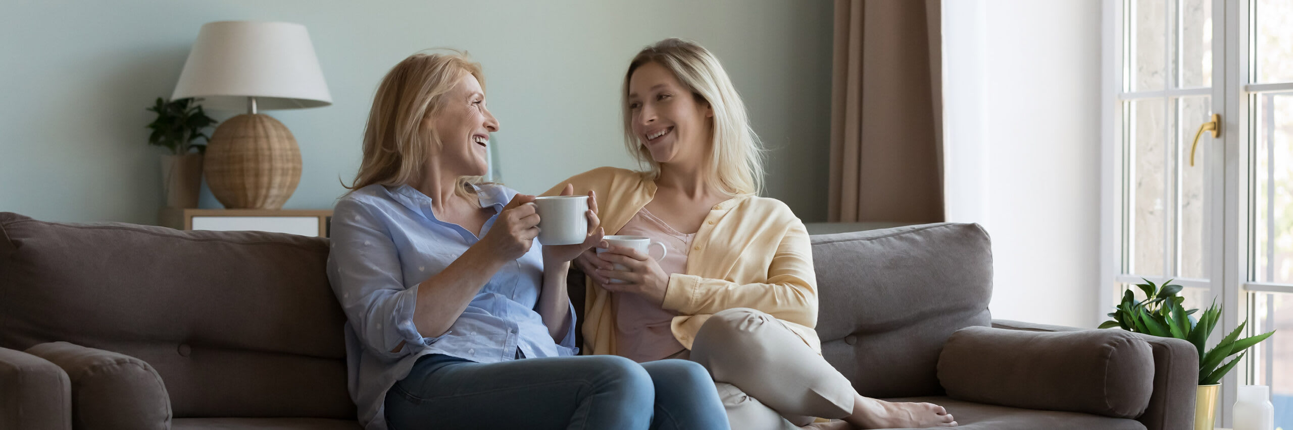 Two women smiling in conversation while sitting on a couch