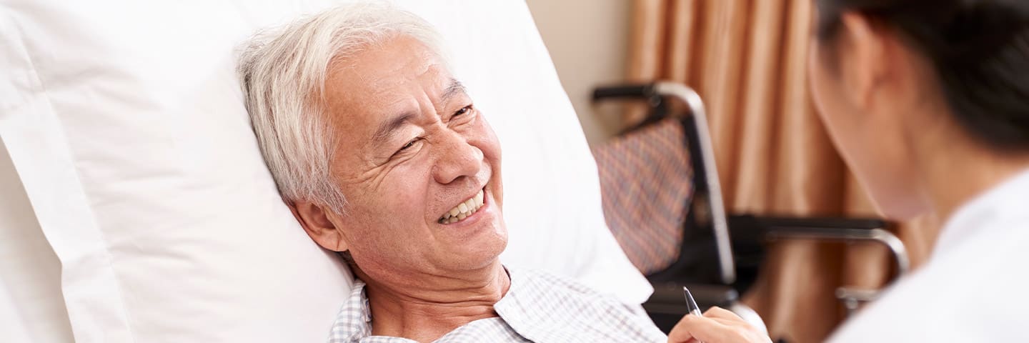 Caregiver tending to senior in bed