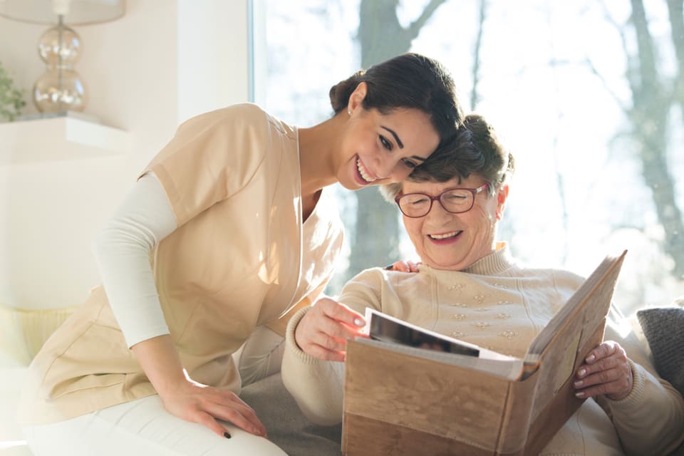 Senior woman and caregiver looking at a book.