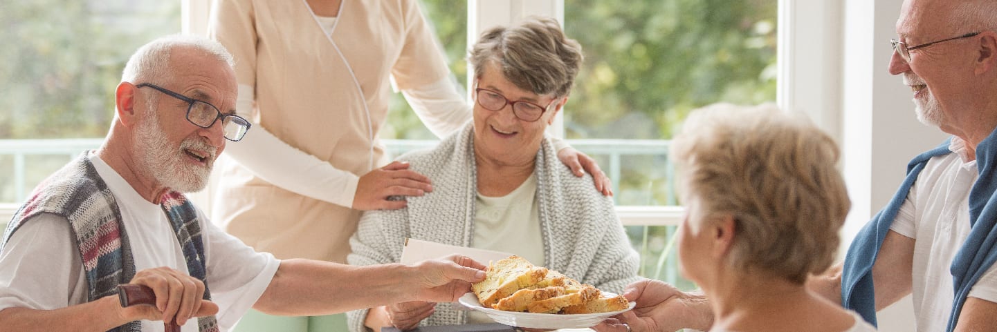 Seniors enjoy food together with caregiver
