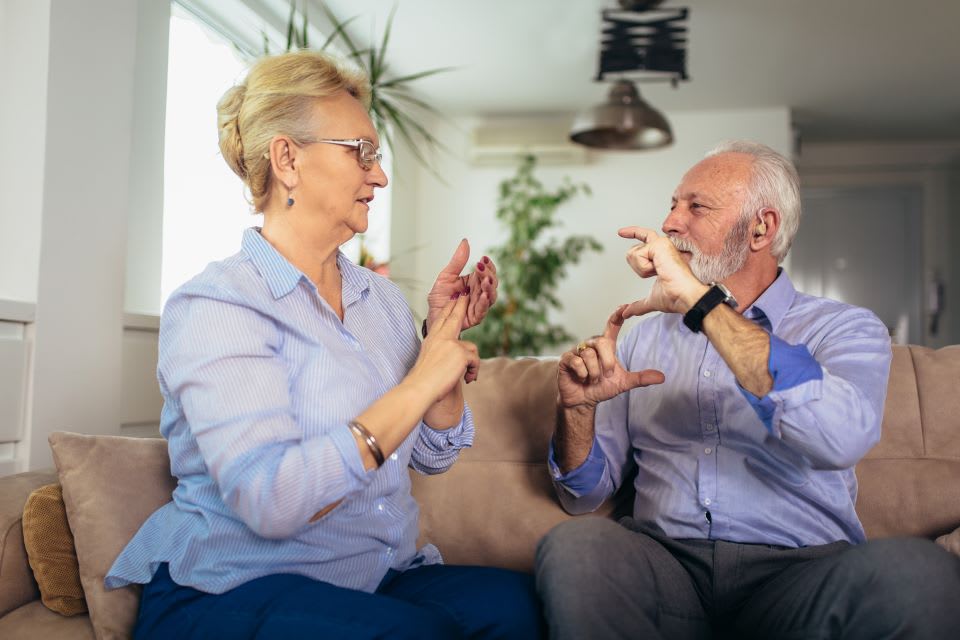 Elderly couple speaking to each other using sign language