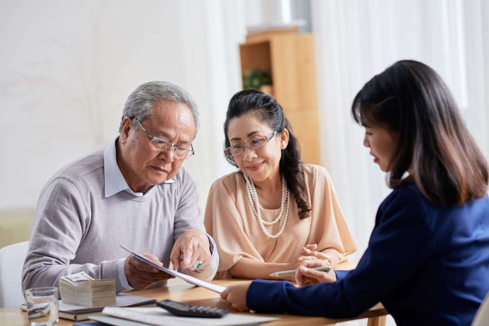 A senior couple review legal paperwork with assisted living community representative