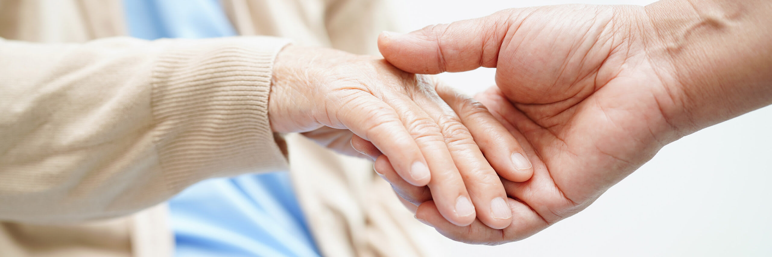 A closeup of a younger hand holding the hand of a senior