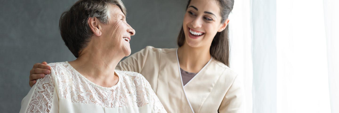 Elderly woman and nurse laughing together