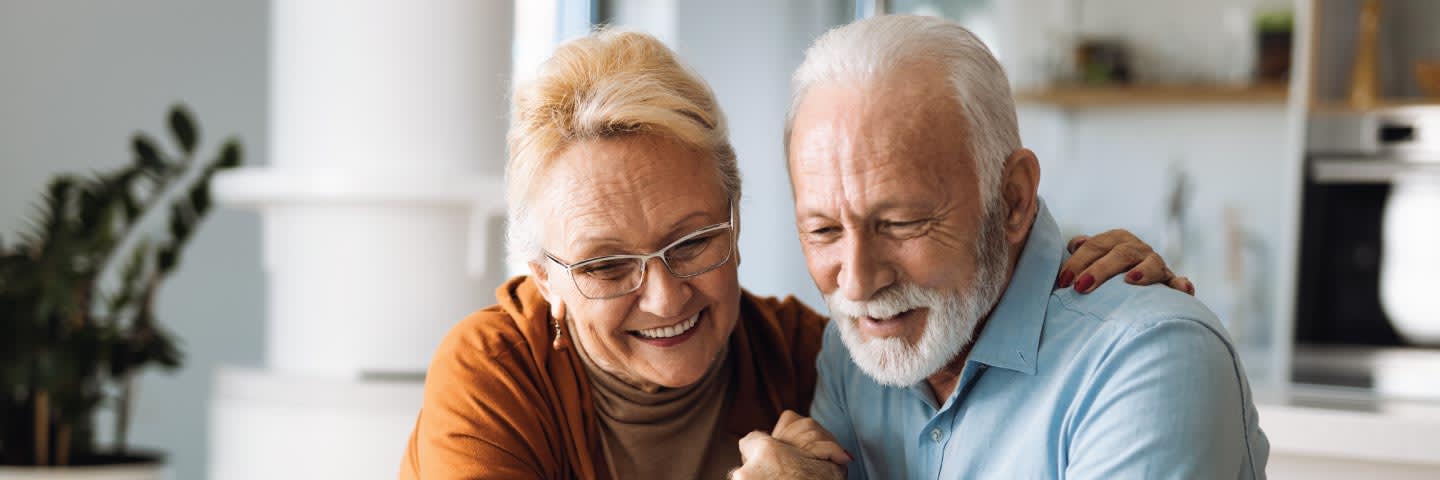 Elderly couple looking at computer smiling