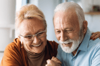 Elderly couple smile as they review documents together