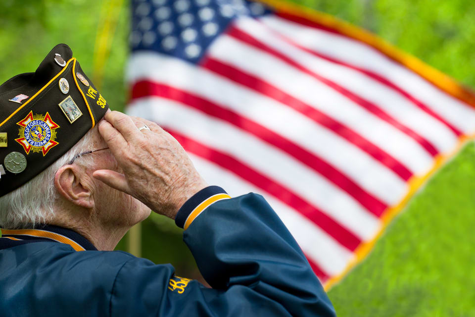 A veteran man salutes the American flag.