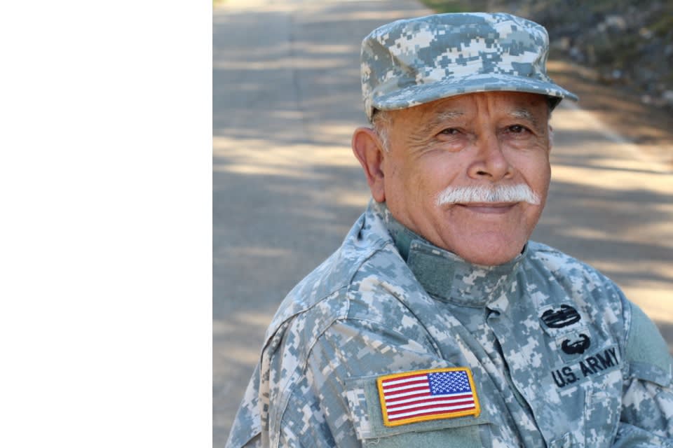 Senior veteran with mustache smiles at camera in uniform