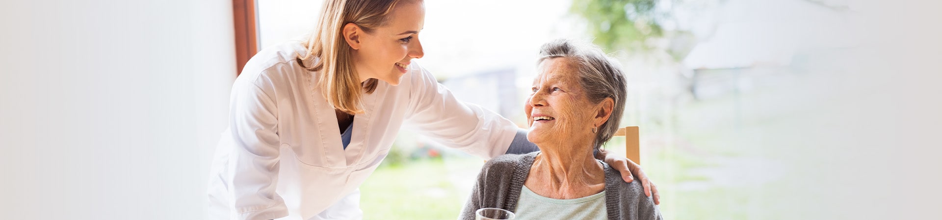 Caregiver and senior at home smiling with breakfast
