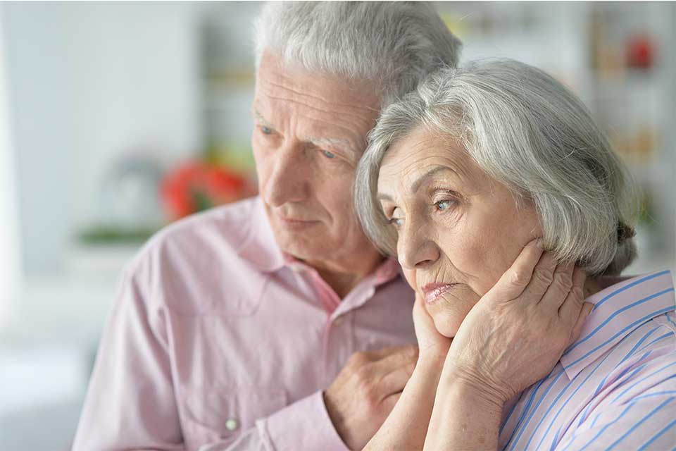 Elderly couple comforting each other after learning of a dementia diagnosis.