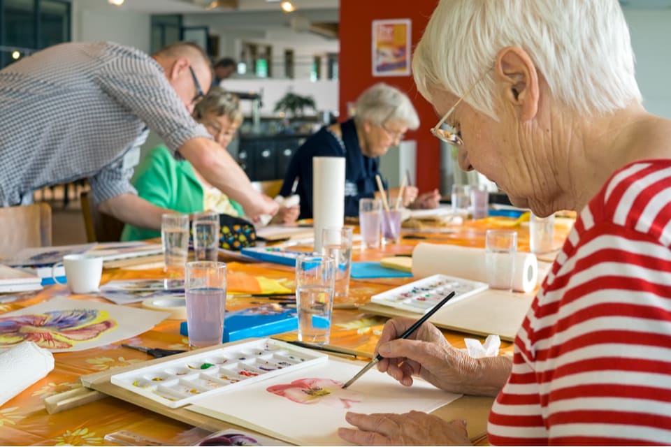 A group of seniors painting and engaging in art therapy.