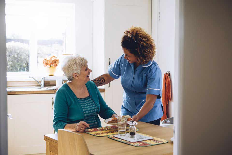 Assisted living nurse helping an elderly woman with her breakfast.