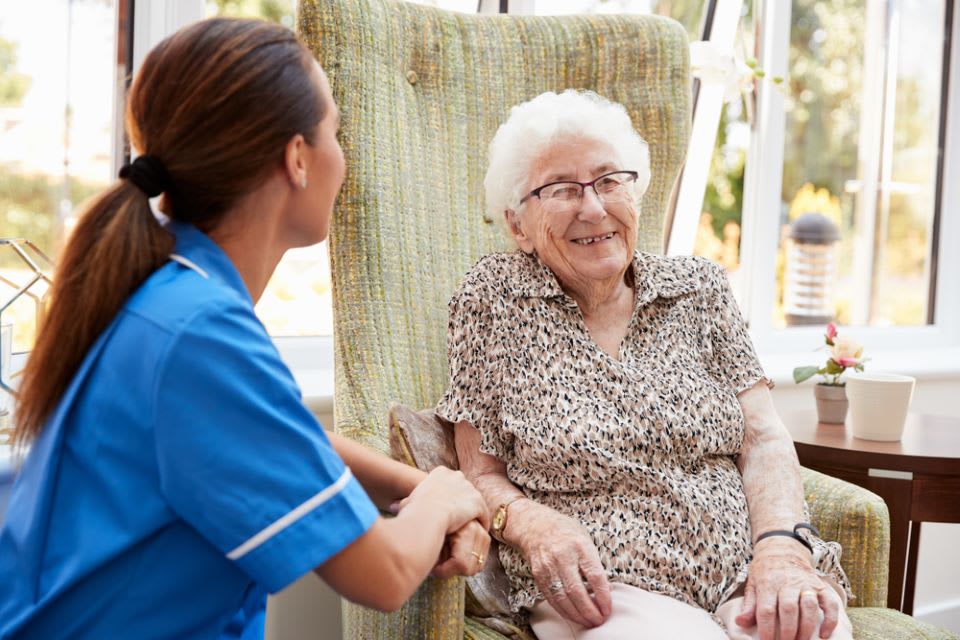 Elderly woman laughing while talking to caregiver