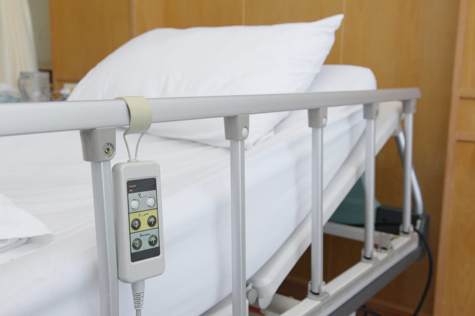 Empty hospital bed with side rails up.