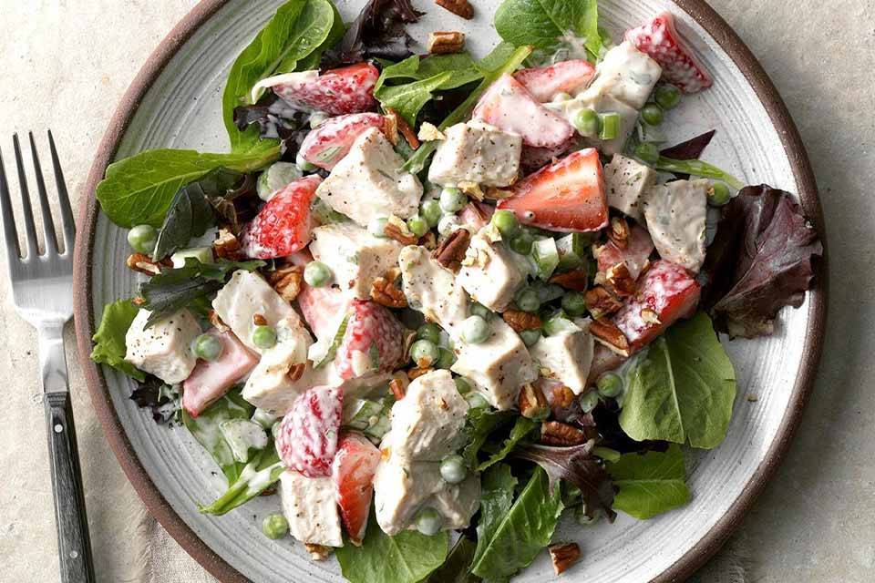 A salad with berries and chicken on a plate