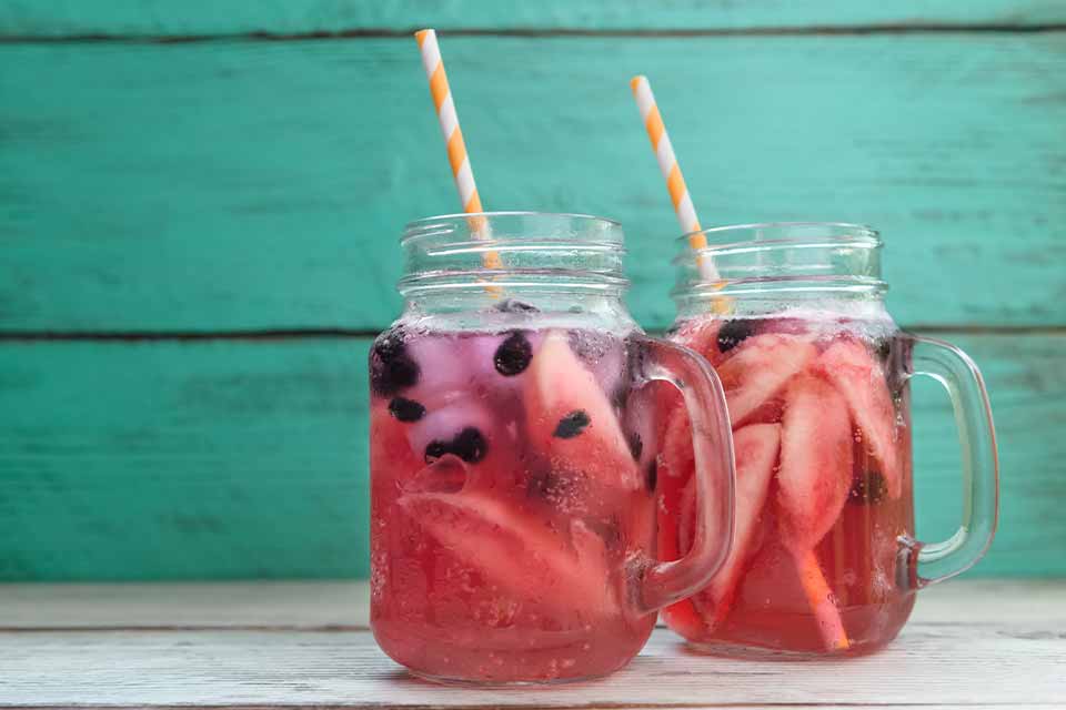 Berry tea in a mason jar with a straw