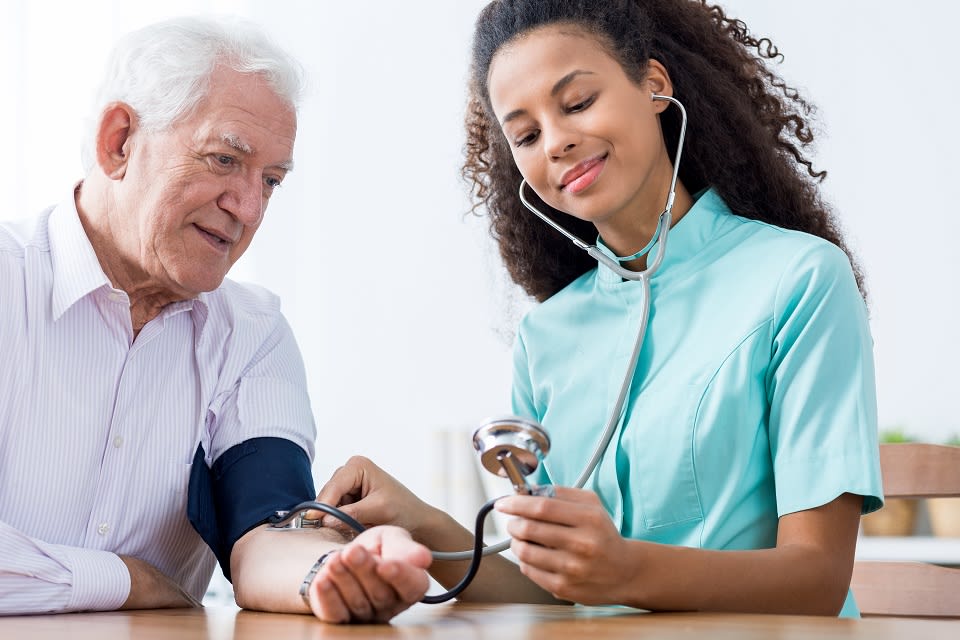 Young woman nurse taking elderly man's blood pressure.