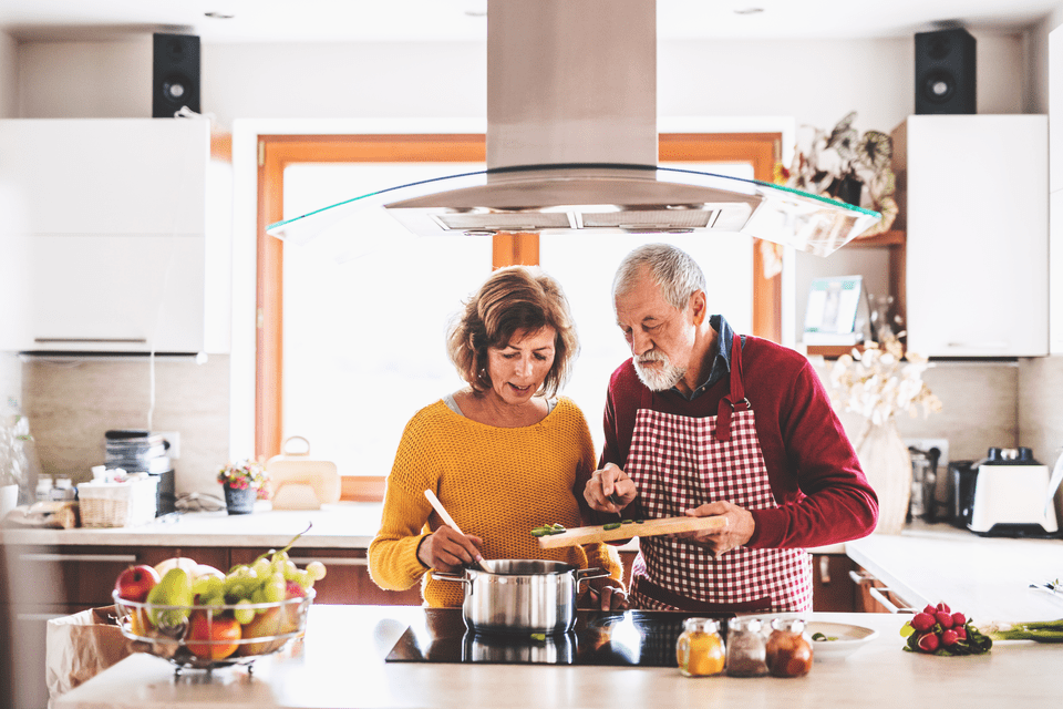 Older man and woman cooking a healthy meal together.