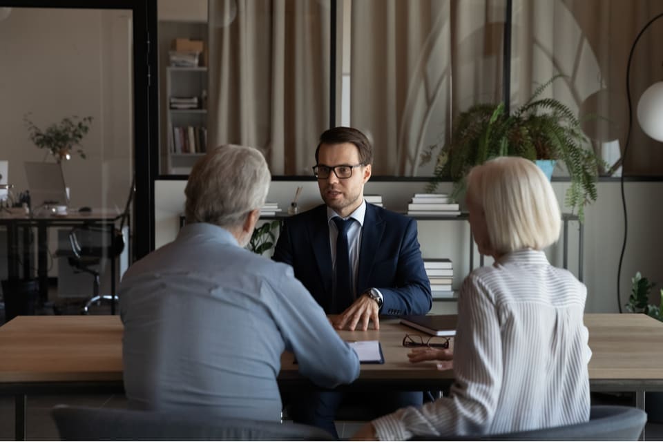 Older couple facing younger man in a business suit.