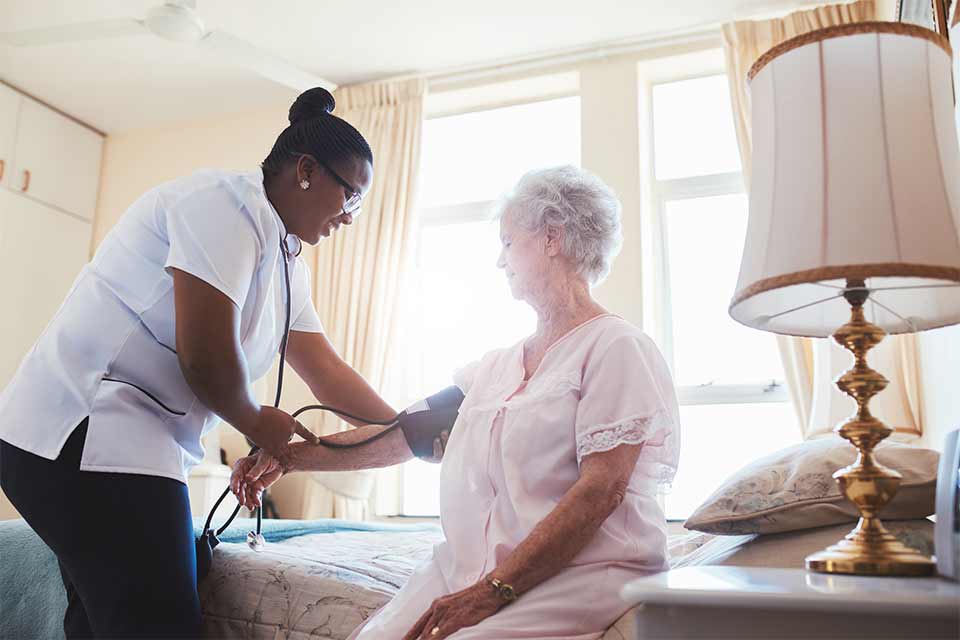 Elderly woman getting her blood pressure taken by a caregiver.