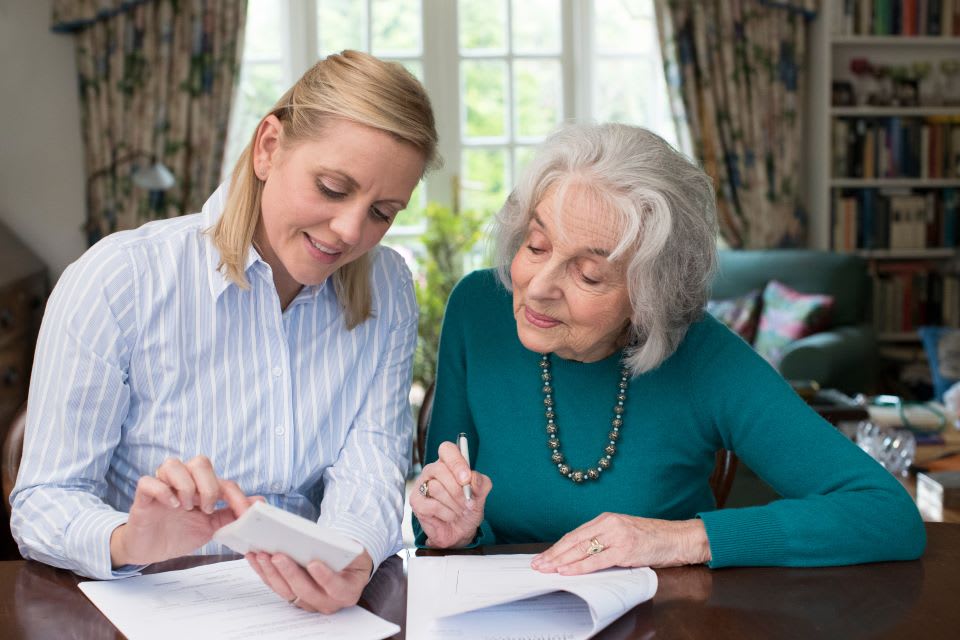Daughter and elderly mother look over a caregiver contract.