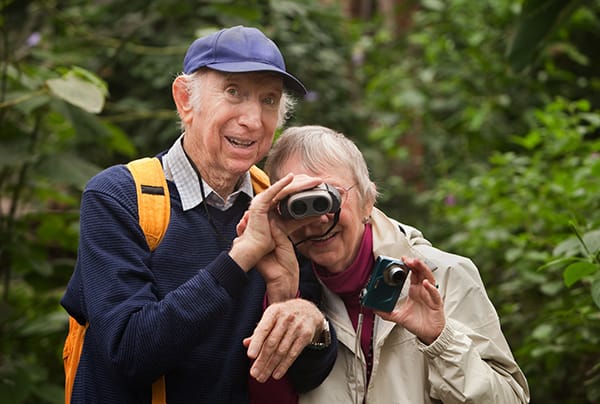 A senior couple sharing a pair of binoculars while outdoors