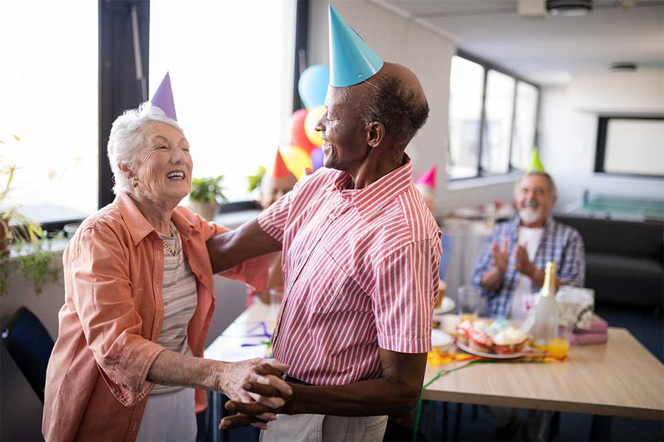 Elderly couple dancing together for a birthday party in a continuing care retirement community.