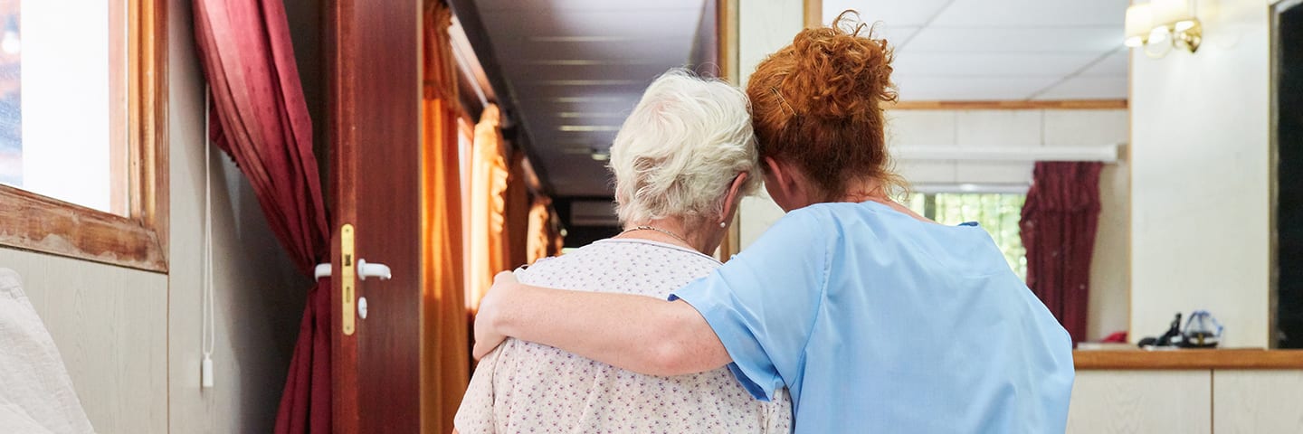 Senior and caregiver sitting on bed