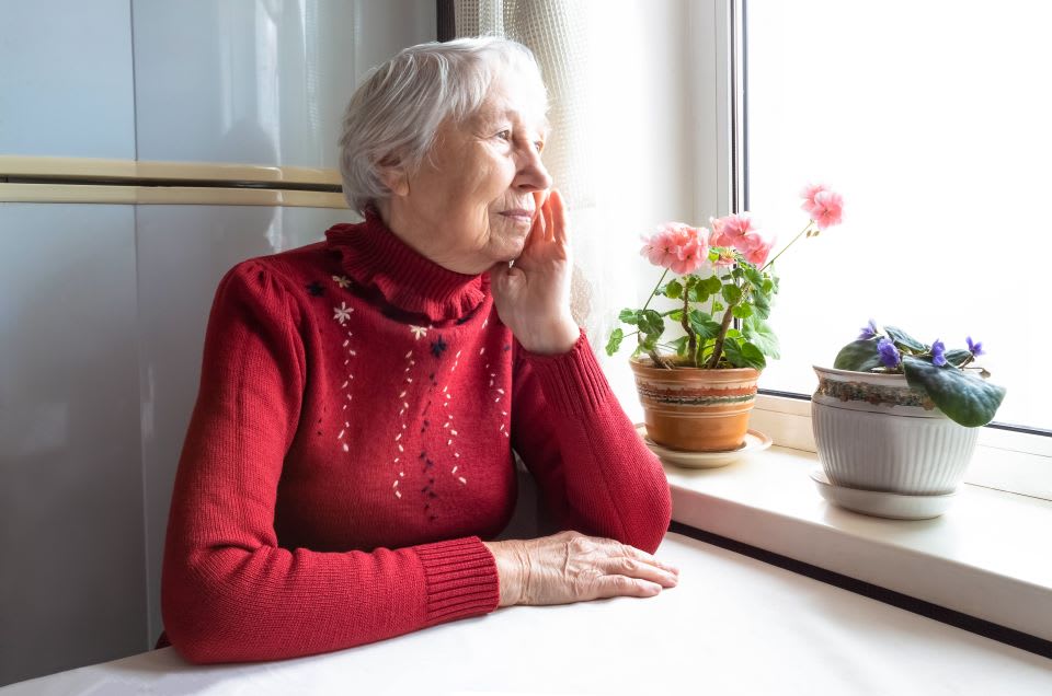 Elderly woman with early dementia symptoms looks out the window