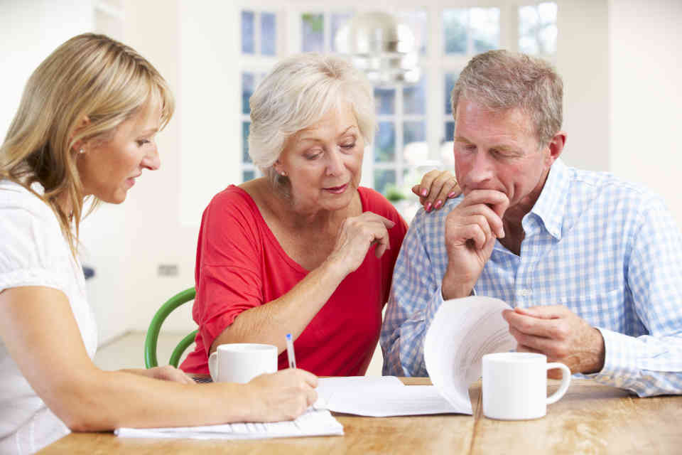 Elderly couple reviewing documents with female advisor
